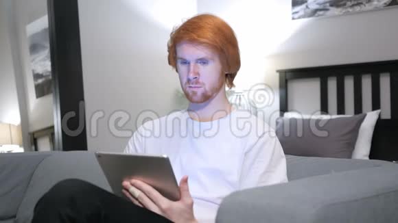 男人在卧室里使用平板电脑对成功的反应视频的预览图