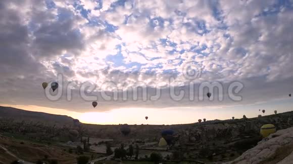 许多热气球飞过土耳其戈尔梅的山谷天空小云的时间流逝视频的预览图