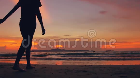 幸福的情侣在夕阳西下的海边相遇并前往海滩的慢动作剪影视频的预览图