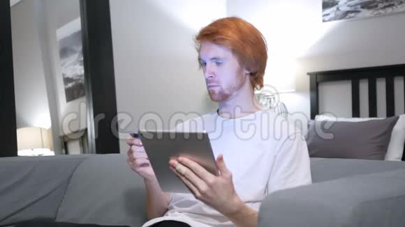 坐着红发男子在平板电脑上网上购物视频的预览图