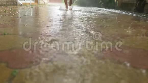 夏雨赤脚穿过水坑温暖的雨雨滴慢动作视频的预览图