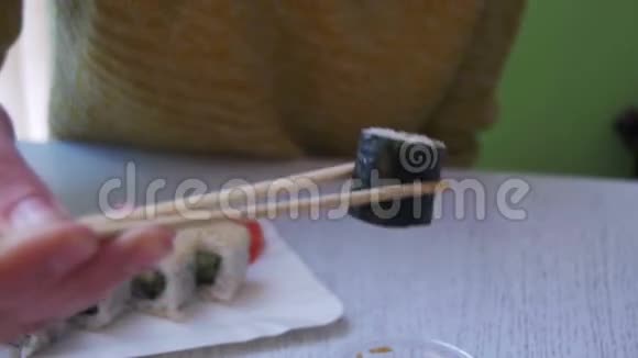 一个女人在日本餐馆用盘子和诺丽一起吃寿司卷慢动作视频的预览图