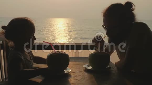 父女俩坐在海景咖啡馆一起喝椰子视频的预览图