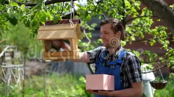 穿着蓝色工作服的年轻园丁在喂鸟视频的预览图