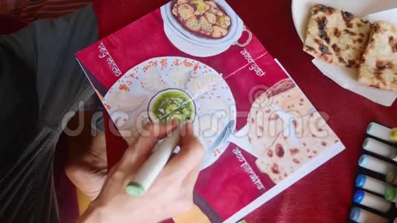 男人坐在咖啡馆里用艺术标记在素描本上描绘印度食物的形象视频的预览图