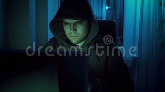一个穿着连帽衫的年轻男性黑客晚上在家里用笔记本电脑工作的4镜头网络犯罪概念视频的预览图