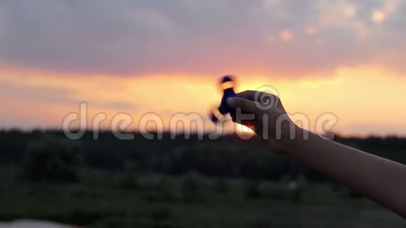 在太阳落山的灿烂日落时旋转的人在雄手中快速旋转视频的预览图