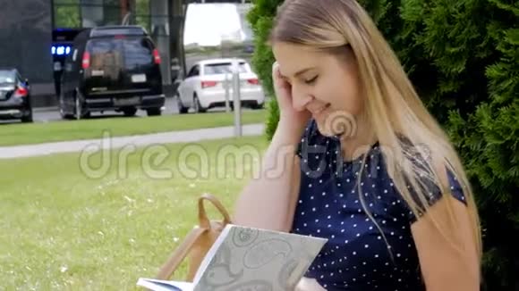 阳光明媚的一天美丽的少女坐在公园的草地上写日记视频的预览图