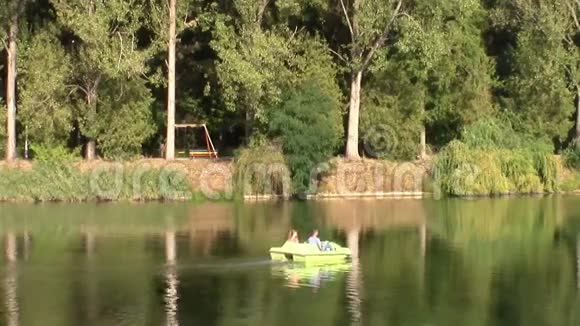 一对年轻夫妇在湖边骑脚踏船视频的预览图