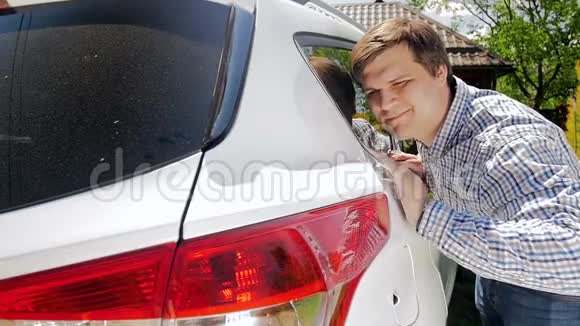 一个微笑的年轻人轻轻抚摸他的车的慢镜头视频的预览图