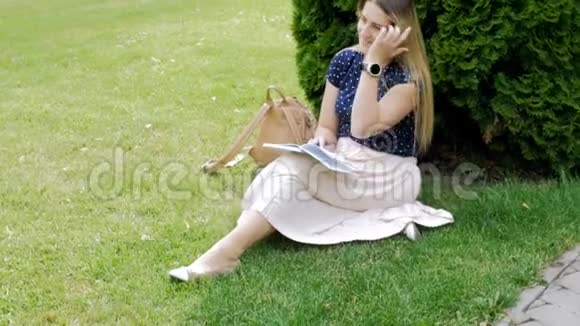 4K美丽的少女坐在公园草地上写日记的镜头视频的预览图