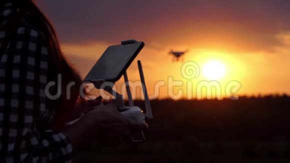 聪明的女人在太阳落山时会用一个面板来操作她的无人机视频的预览图