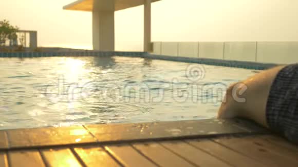 那人坐在池边双脚在水中房子屋顶上的豪华游泳池和一个视频的预览图