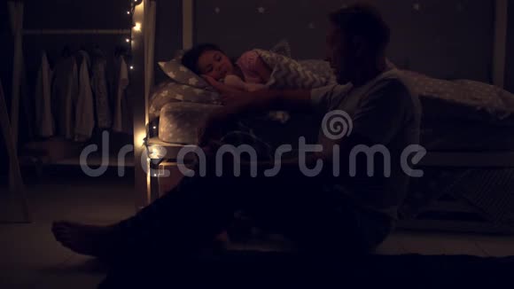 他的父亲坐在他熟睡的女儿旁边视频的预览图