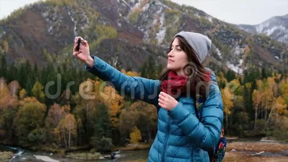 美丽的女人用手机在山上自拍吸引人的女游客做自我画像视频的预览图