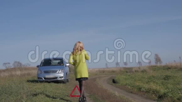 迷人的商务女性通过手机呼救女孩在农村公路上的破车附近慢动作视频的预览图