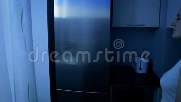 夜间从冰箱里拿食物的小睡女人慢镜头视频的预览图