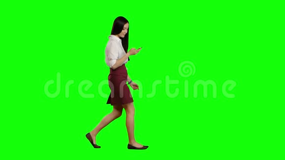 女孩走着拿着电话看照片绿色屏幕侧视图视频的预览图