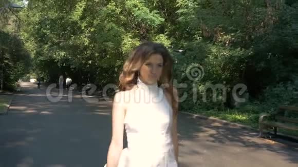 公园里跑着一个穿着白色连衣裙的年轻女子视频的预览图