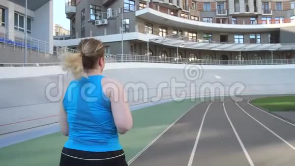 超重女性沿着体育场跑道慢跑视频的预览图
