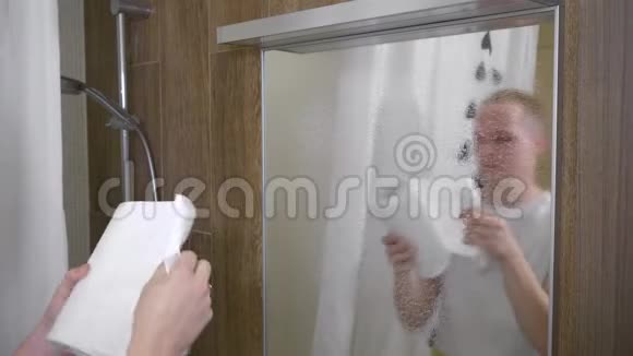 一个人打扫浴室里的镜子一个年轻人用纸巾清洁浴室镜子4K视频的预览图