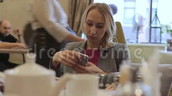女商人穿着夹克用手机在咖啡馆里思考视频的预览图