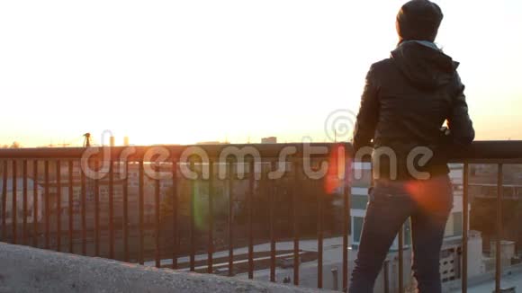 站在屋顶桥上看日落的年轻女子视频的预览图