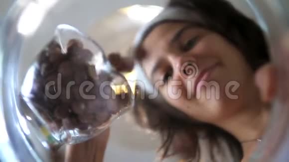 年轻女子在玻璃碗里撒榛子视频的预览图