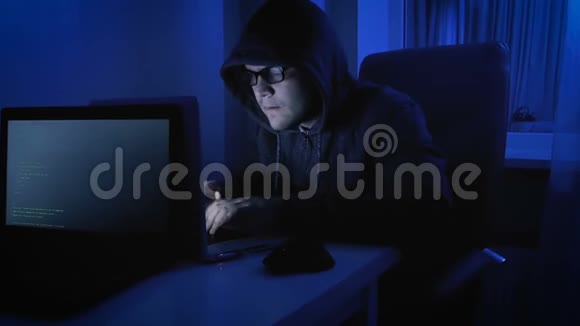 有趣的4k镜头男性假装是黑客天啊戴帽子的人晚上在用笔记本电脑视频的预览图