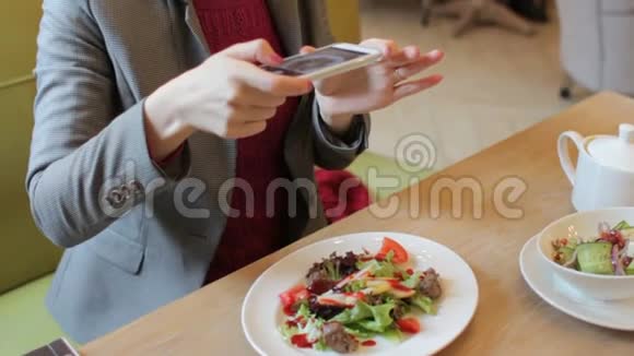 女博主的手在咖啡厅用手机拍下美味沙拉视频的预览图