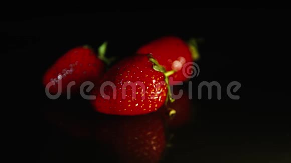 三个草莓躺在黑暗的背景上高清高清视频的预览图