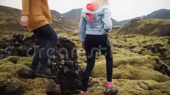 两位女游客一起在冰岛徒步旅行女孩穿过熔岩场覆盖着苔藓视频的预览图