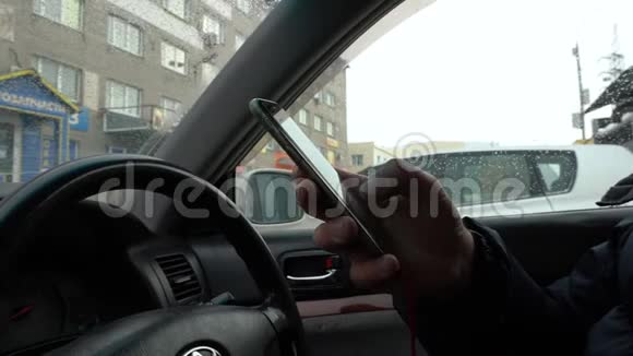 一个男人坐在车里用智能手机视频的预览图