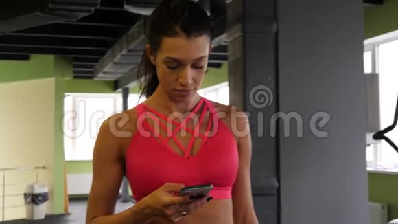 适合运动混合种族的女人正在运动健身房的手机上走短信视频的预览图