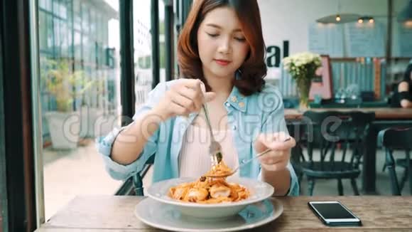 吸引人的美丽亚洲女性食品博客使用智能手机或相机照片和录音制作食品博客视频视频的预览图