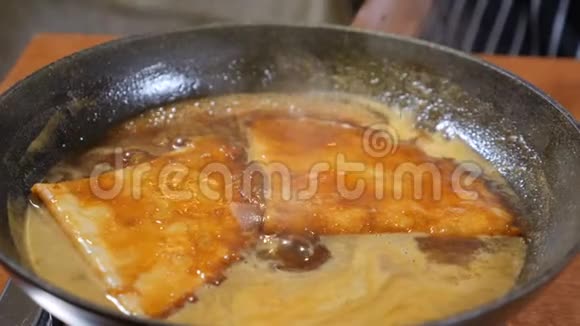 餐厅烹饪理念煎饼在沸腾的焦糖里带手套的厨师用勺子把焦糖倒在煎饼上慢慢视频的预览图