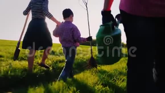 一个友好的家庭要种一棵树后视在前景的浇水罐一个小男孩在跑视频的预览图