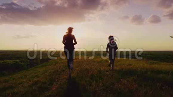 后景妈妈和女儿在日落时跑在风景如画的地方积极的生活方式和健康的家庭4K慢动作视频的预览图