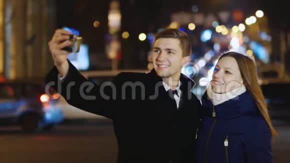一对年轻夫妇在夜晚的城市背景下为自己拍照视频的预览图
