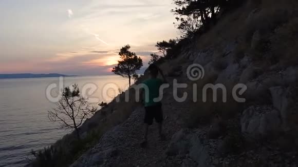 一个好人来自岩石山上的海滩俯瞰大海欣赏日落达尔马提亚克罗地亚视频的预览图