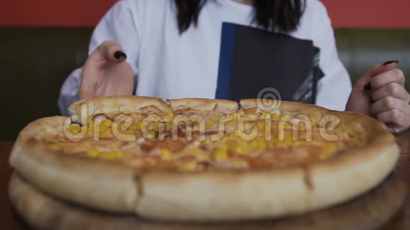 特写切片比萨饼是在一个圆形的木盘上提供的女人手拿一块美味的披萨视频的预览图