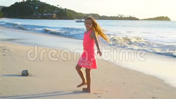 可爱的快乐小女孩在日落时在白色的海滩上嬉戏流动电视视频的预览图