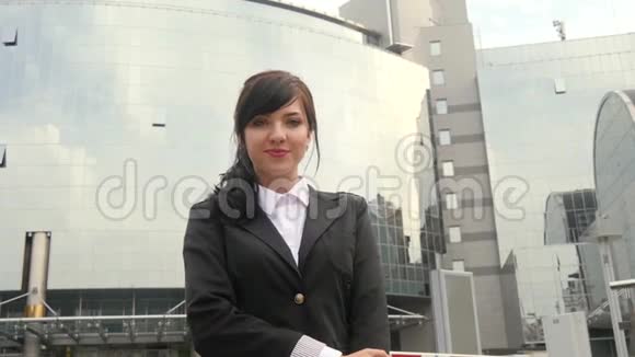 美丽的微笑商务女性站在办公楼旁视频的预览图