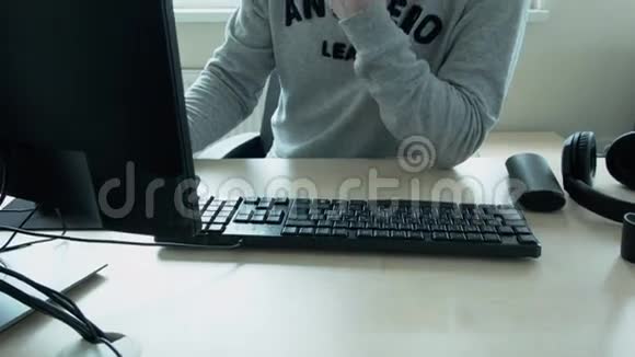 程序员穿着灰色夹克上面写着安蒂英雄在办公室的一台电脑上工作戴眼镜的年轻人视频的预览图
