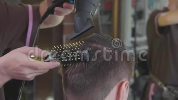 理发师给理发店的男顾客做梳子和吹风机的发型视频的预览图