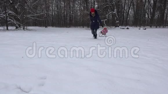 在冬天下雪的日子里妈妈和女婴在雪橇上4K视频的预览图