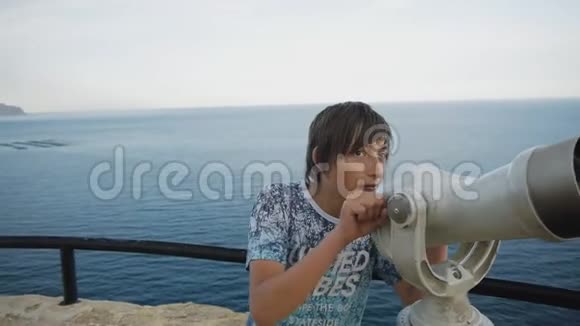 十五岁的男孩从高高的观景台上看着海岸进入望远镜视频的预览图
