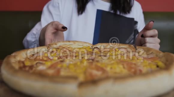 特写切片比萨饼是在一个圆形的木盘上提供的女人手拿一块美味的披萨视频的预览图