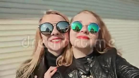两个年轻漂亮的女朋友戴着太阳镜脸上洋溢着乐趣和风骚在镜头前摆姿势做什么视频的预览图