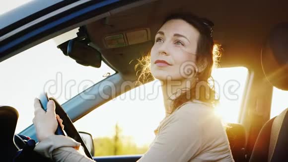 一个忧郁而平静的中年妇女坐在车里他通过敞开的门崇拜大自然日落前的傍晚视频的预览图